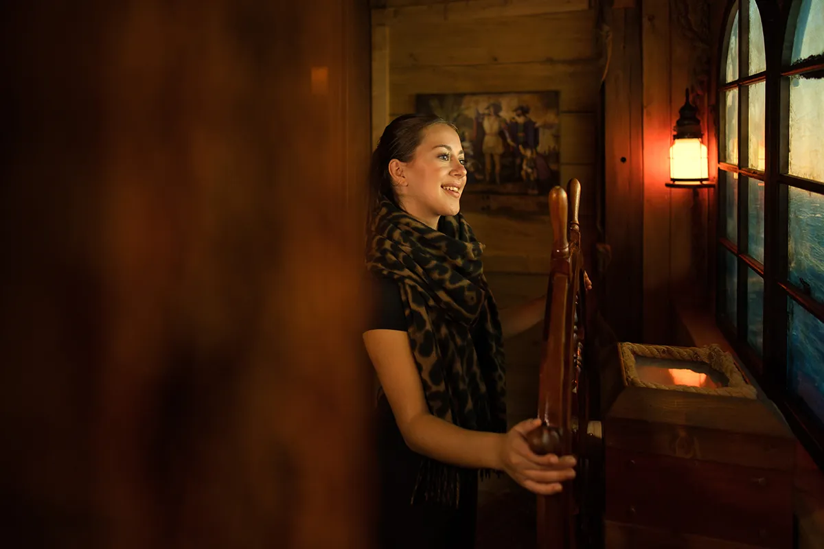 Eine Szene im Escape Room "Open The Door" in Wien: Eine junge Frau steht am Steuerrrad eines Schiffes.